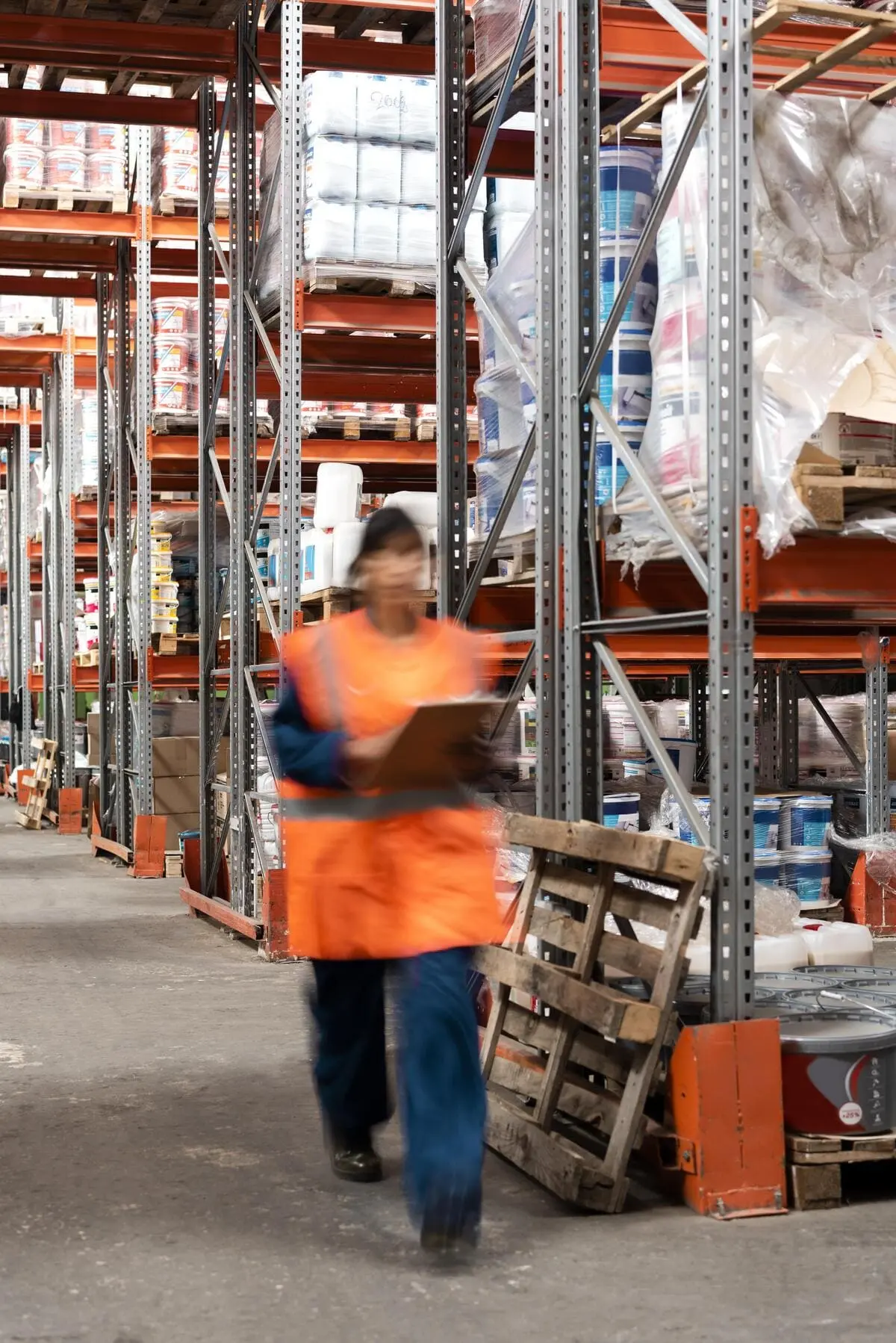 Femme avec un gilet orange qui marche dans un hangar de marchandises