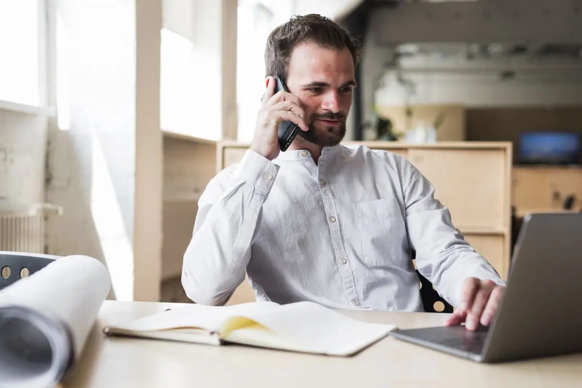 Un homme au téléphone devant son bureau